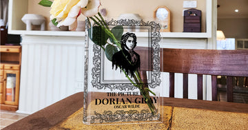 Acrylic book vase styled as 'The Picture of Dorian Gray' with a rose on a wooden table