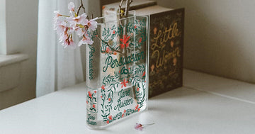 Acrylic Persuasion book vase with flowers on a white table, Little Women book in background