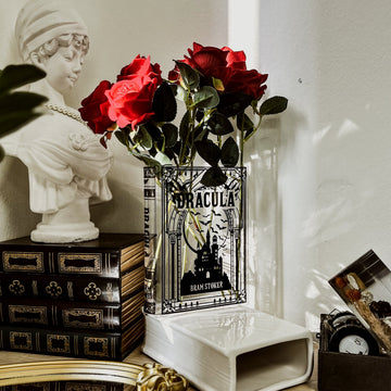 Book-shaped Dracula vase with red roses on vintage books beside a white bust