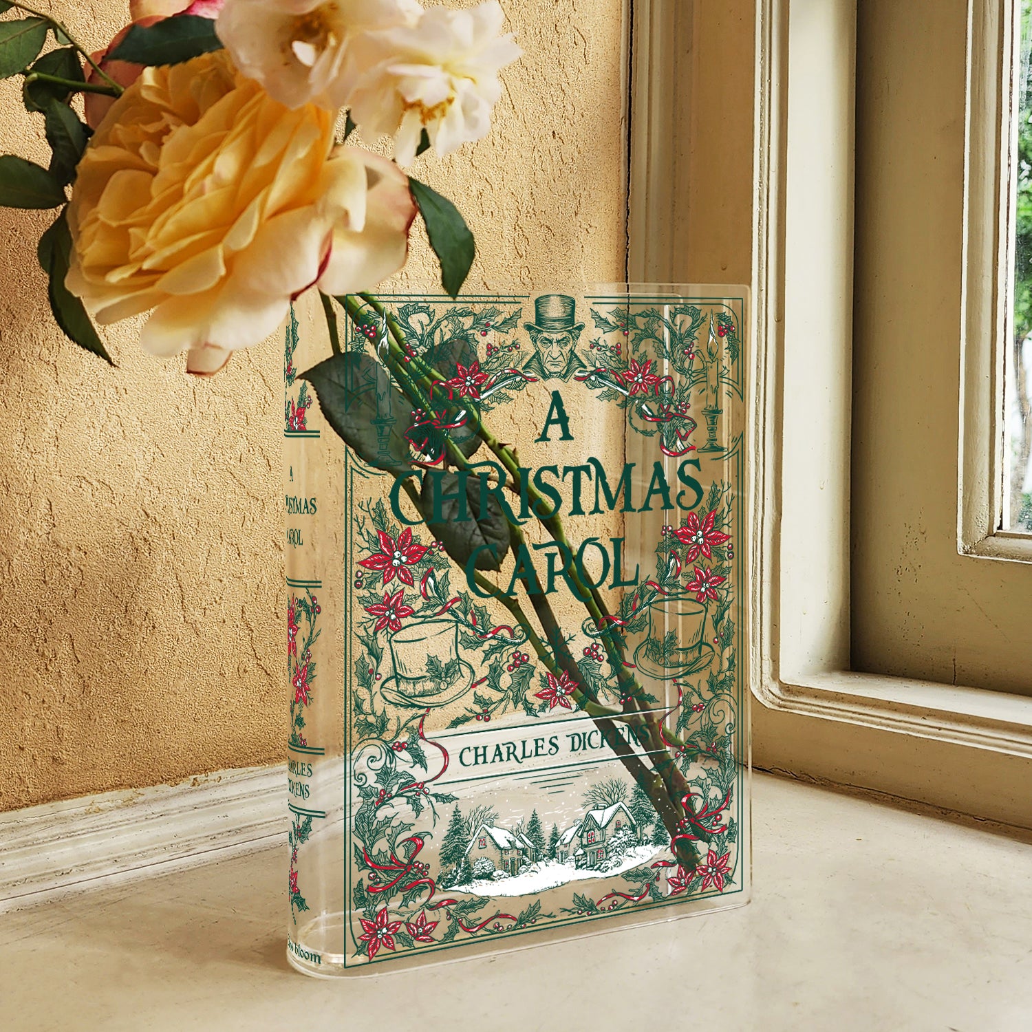 Acrylic book vase styled as 'A Christmas Carol' with yellow roses by a window