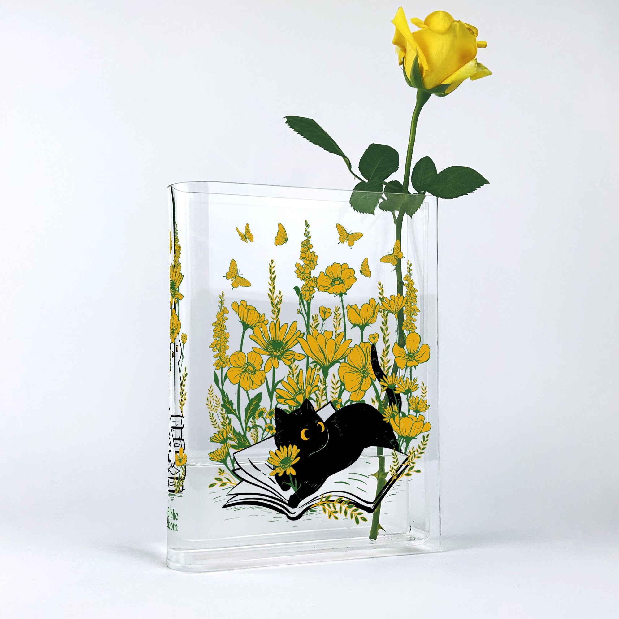 Acrylic book vase with yellow flowers, butterflies, and black cat illustration, holding yellow rose