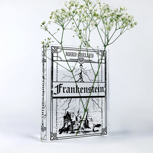 Frankenstein acrylic book vase with white flowers and black graphic design on clear background