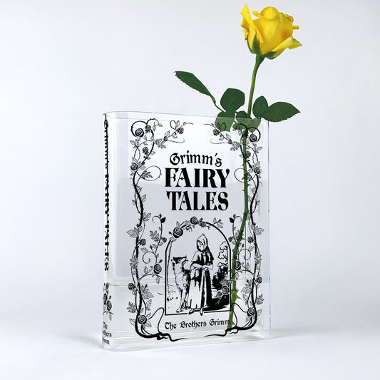 Acrylic book-shaped vase with Grimm's Fairy Tales cover and a single yellow rose inside
