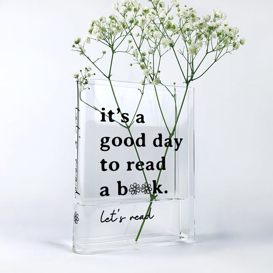Acrylic book-shaped vase with baby's breath flowers and 'it's a good day to read a book' text.
