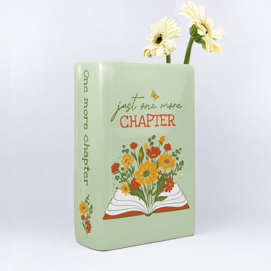 Ceramic book-shaped vase with 'just one more chapter' text, yellow flowers, floral design