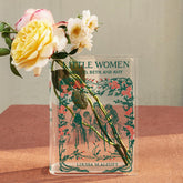 Acrylic book vase styled as Little Women by Louisa M. Alcott holding fresh roses on a table.
