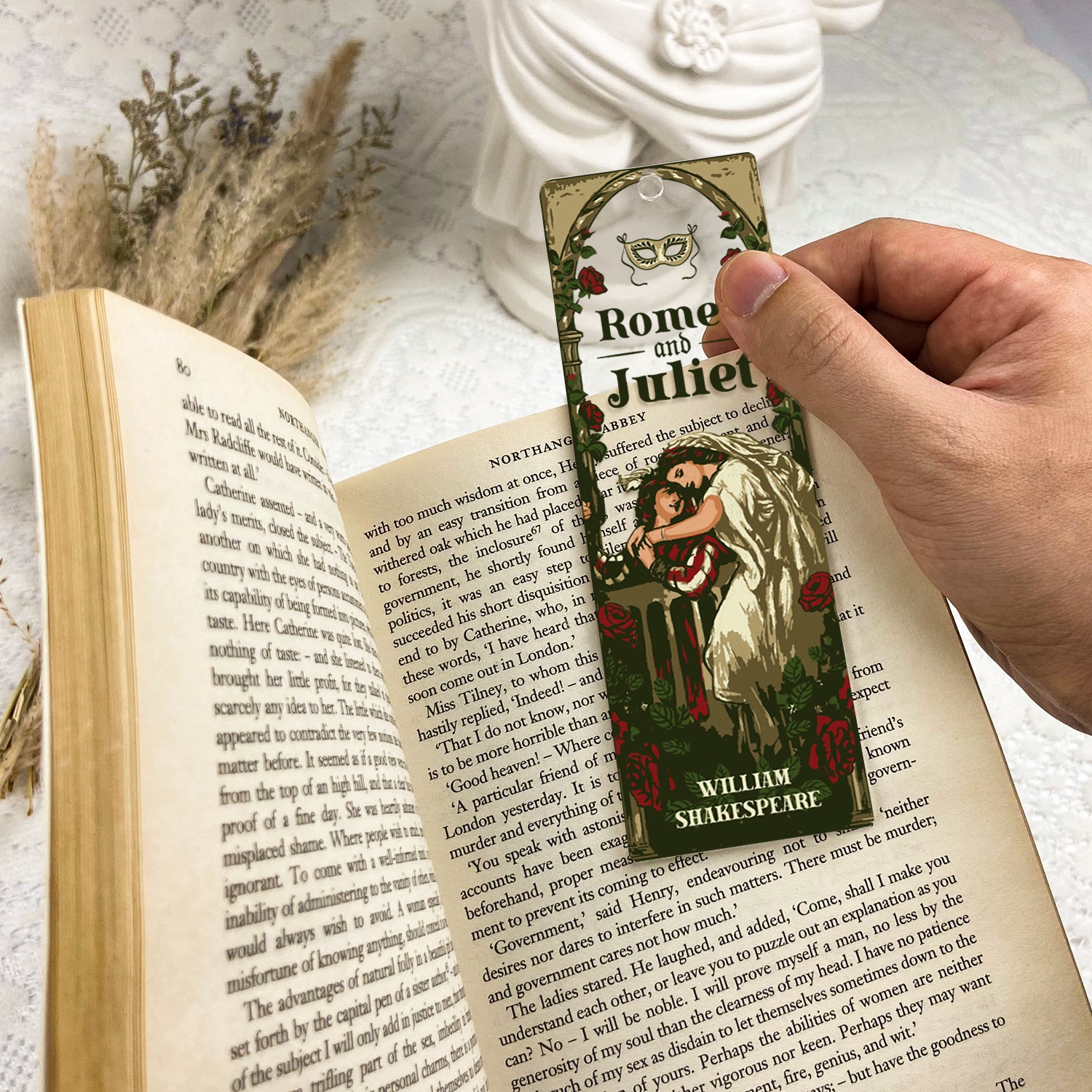 Romeo and Juliet bookmark held over open book, floral decor, literature-themed accessory
