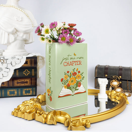 Ceramic book vase with 'just one more chapter' text, flowers inside, on ornate mirror tray