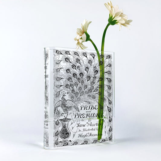 Acrylic book vase shaped like Pride and Prejudice with floral design, holding two white flowers.