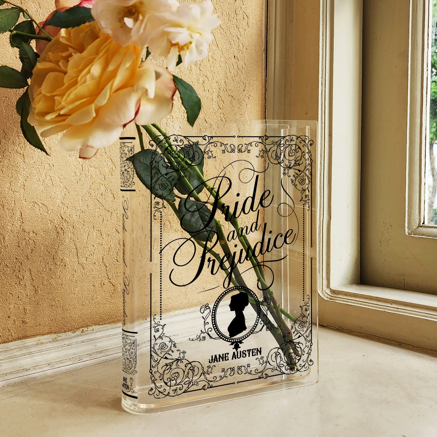 Acrylic book vase shaped like Pride and Prejudice by Jane Austen with flowers on windowsill