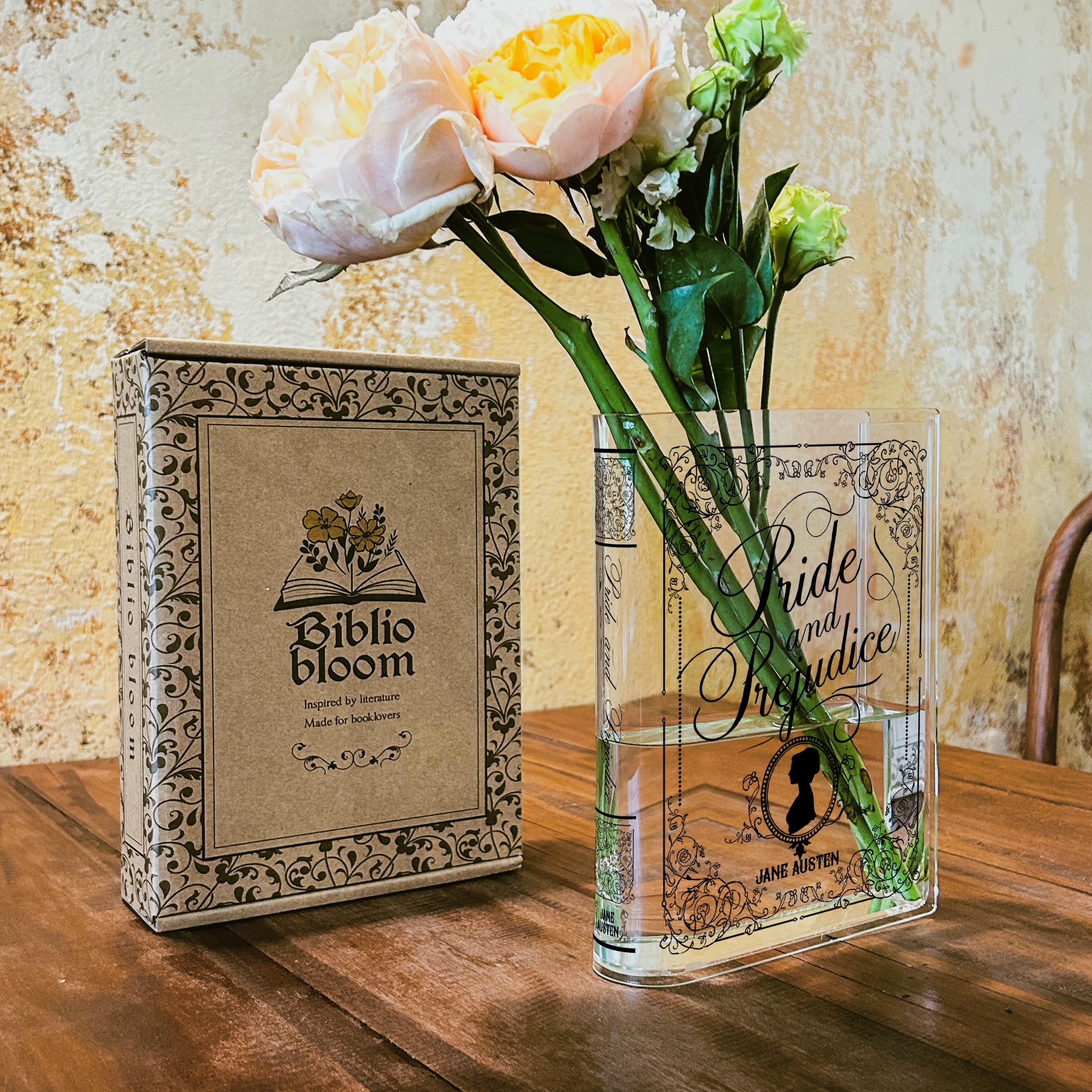 Acrylic Pride and Prejudice book vase with flowers beside Biblio Bloom box on wooden table