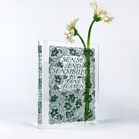 Acrylic book vase shaped like Sense and Sensibility by Jane Austen with white daisies