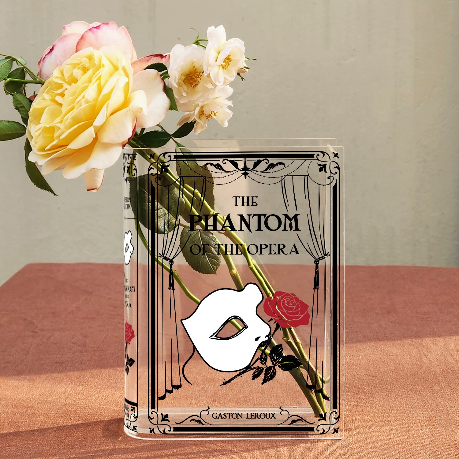 Phantom of the Opera acrylic book vase with roses on a textured table