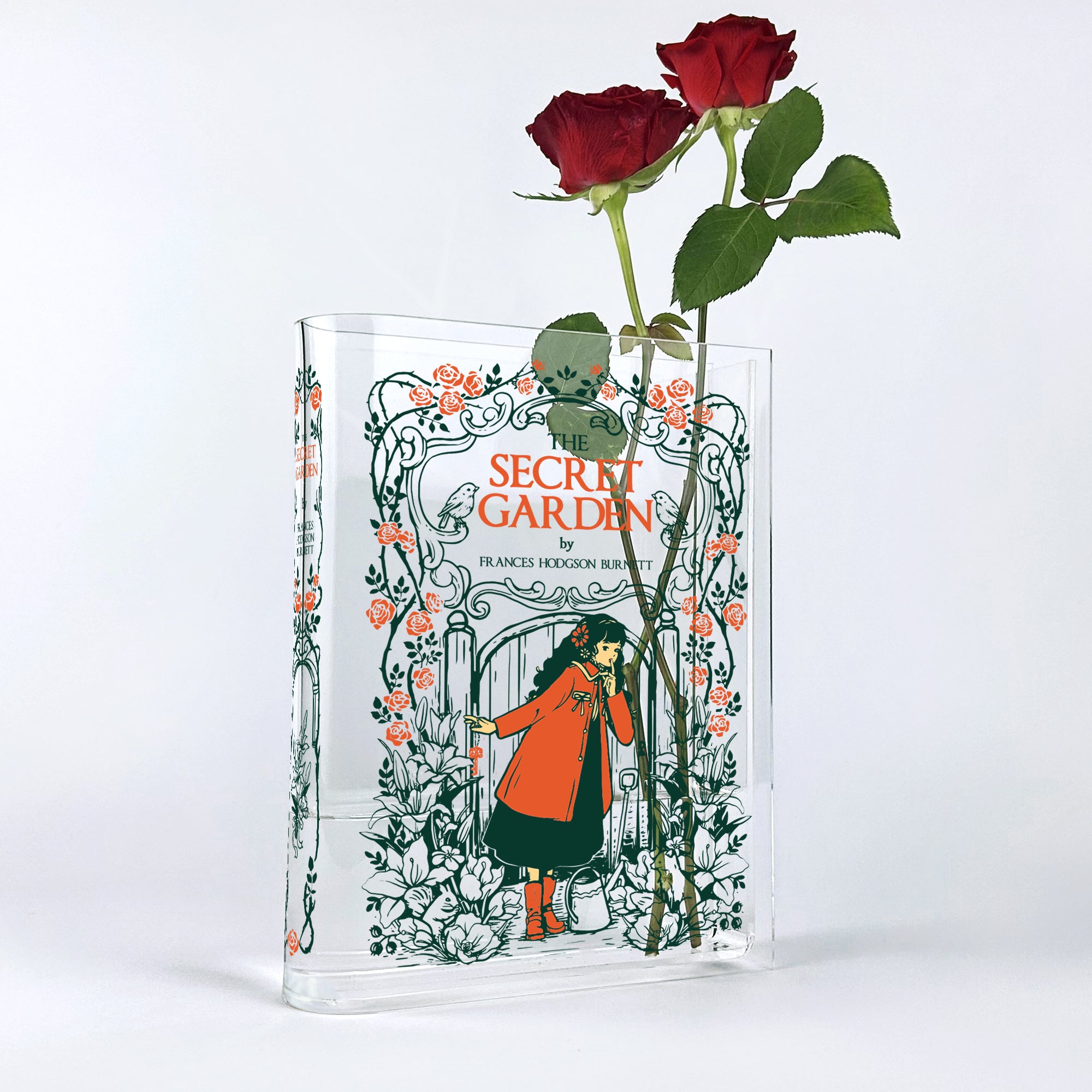 The Secret Garden acrylic book vase with red roses against a white background