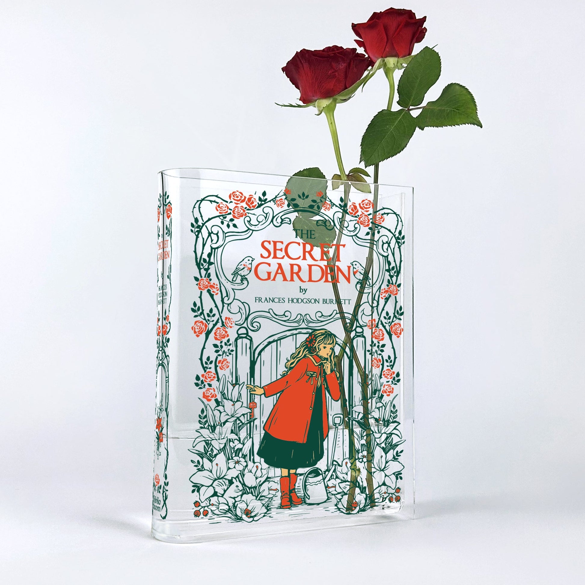 Acrylic book vase with The Secret Garden cover design, holding two red roses