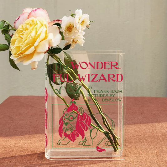 Acrylic book vase styled as The Wonderful Wizard of Oz holding yellow and white roses.