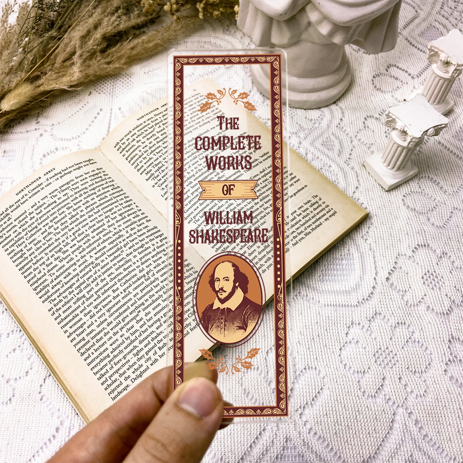 The Complete Works of William Shakespeare bookmark held over open book on lace tablecloth