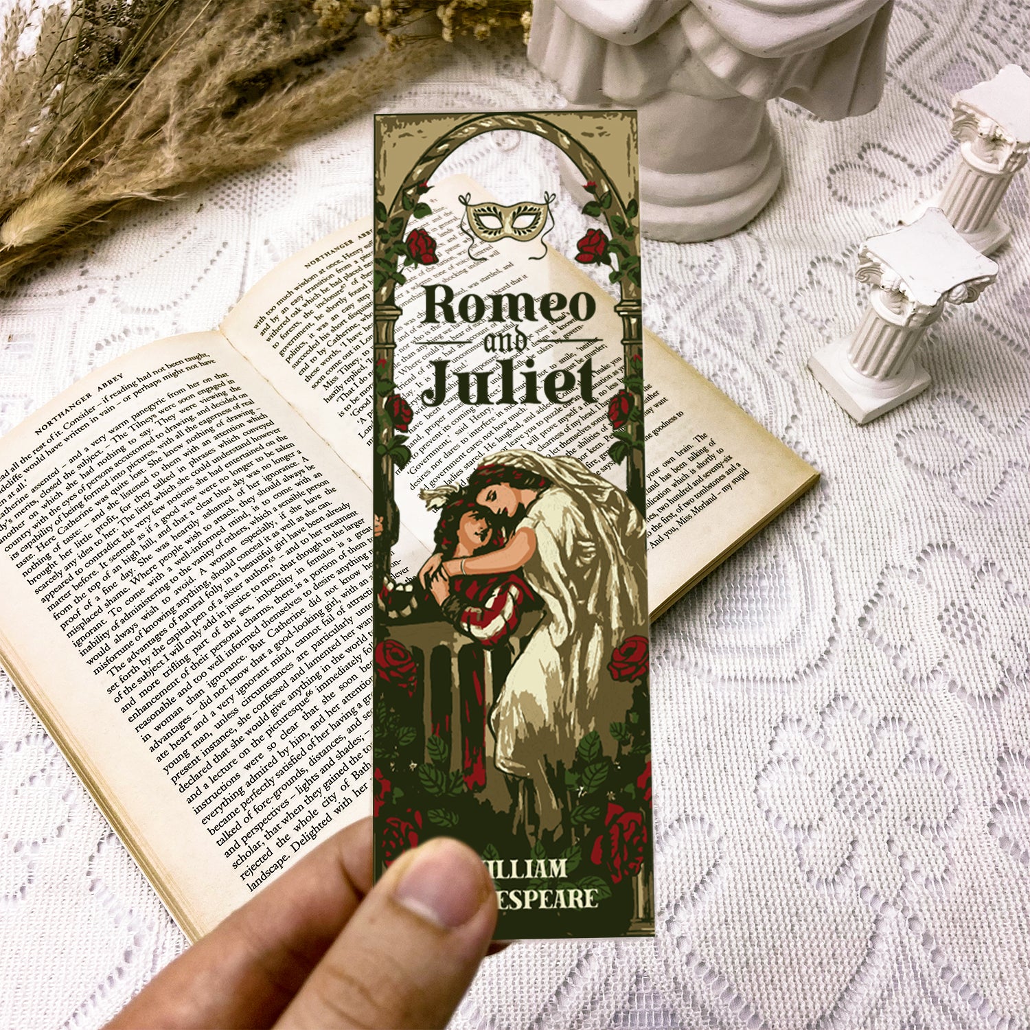 Romeo and Juliet illustrated bookmark held over open book on lace table with classical decor