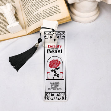 Beauty and the Beast rose bookmark with black tassel beside open book and white statues