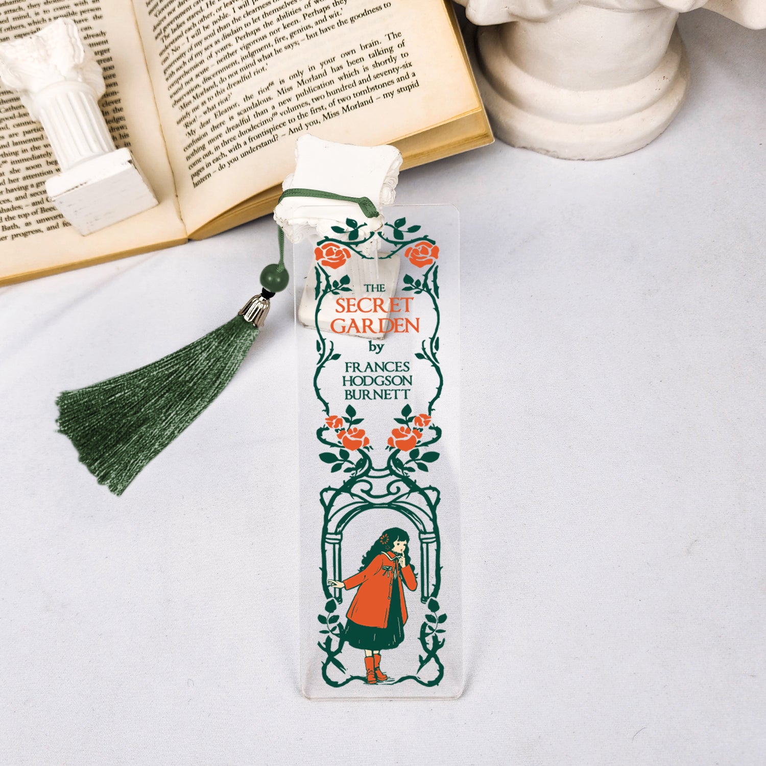 The Secret Garden bookmark with green tassel, beside open book and white column decor